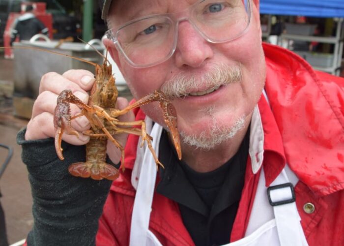 a man jokingly poses with a crawfish