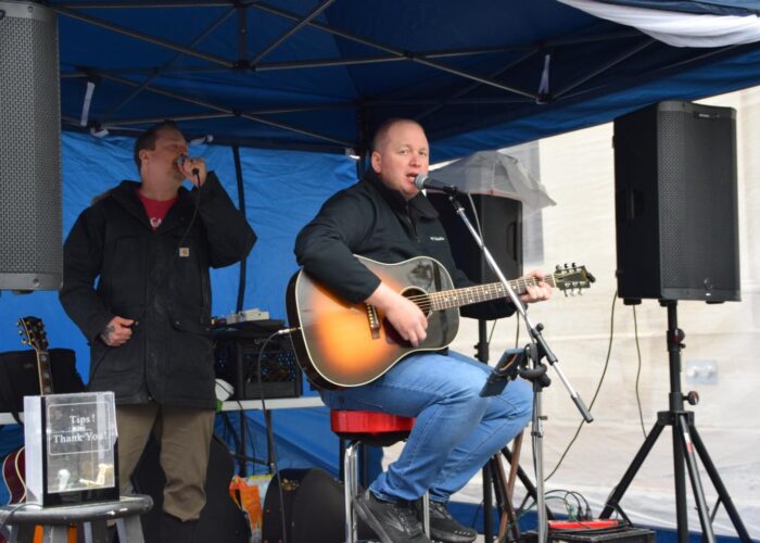a man playing guitar under a tent