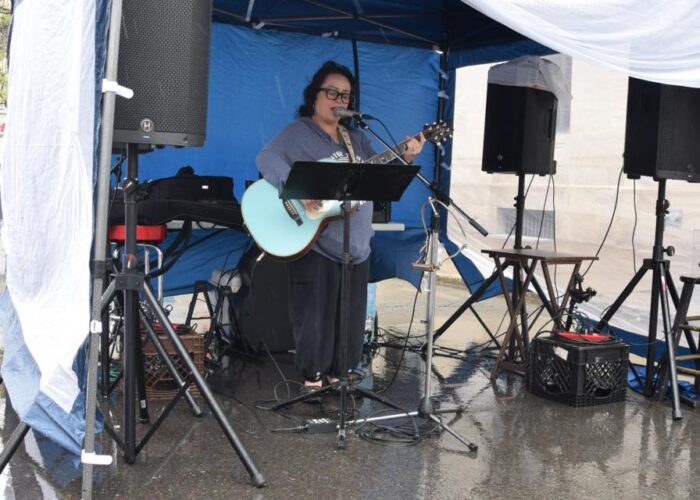 a woman playing guitar under a tent