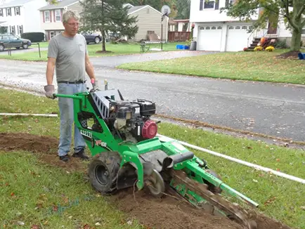 a man using a machine to dig a drainage ditch